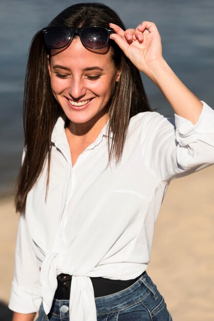 Vorderansicht der Smiley-Frau mit Sonnenbrille am Strand