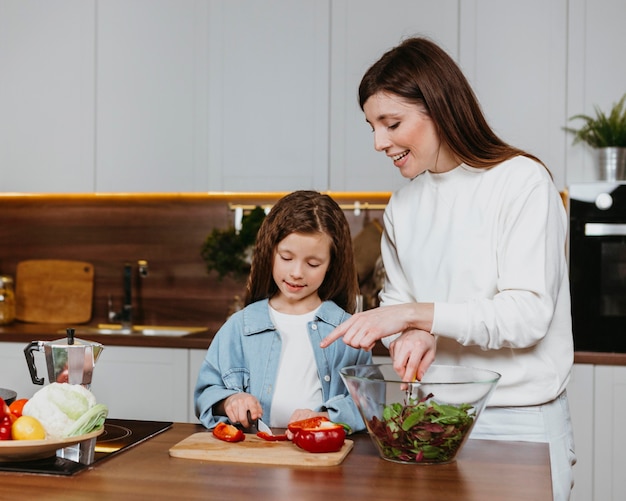 Vorderansicht der Smiley-Mutter und der Tochter, die Essen in der Küche zubereiten