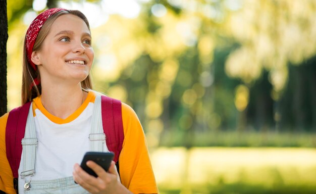 Vorderansicht der Smileyfrau draußen mit Smartphone