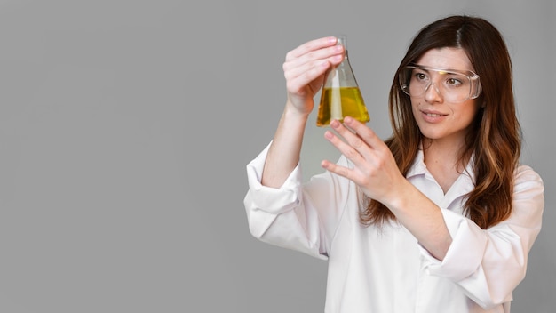 Kostenloses Foto vorderansicht der wissenschaftlerin mit reagenzglas und kopierraum