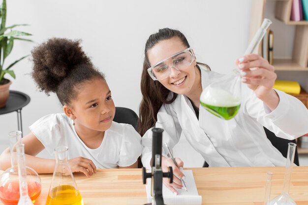 Vorderansicht der Wissenschaftlerin und des Mädchens, die Spaß mit Chemieexperimenten haben