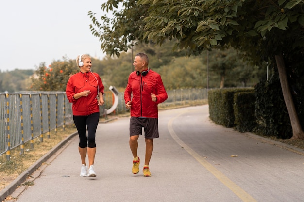 Vorderansicht des älteren Paares, das draußen im Park zusammen joggt