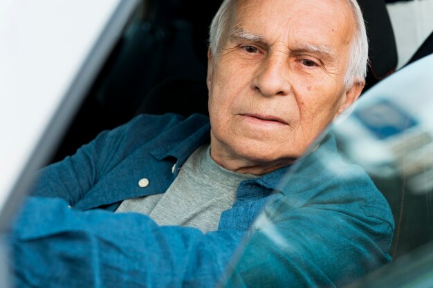 Vorderansicht des alten Mannes im persönlichen Auto