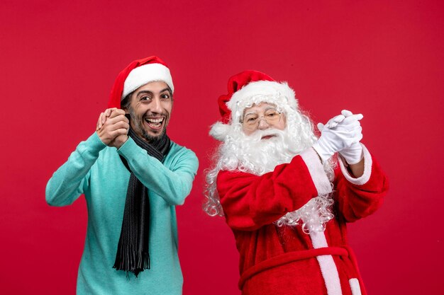 Vorderansicht des alten Weihnachtsmanns mit Mann, der auf der roten Wand steht