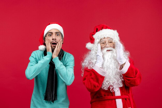 Vorderansicht des alten Weihnachtsmanns mit Mann, der auf der roten Wand steht