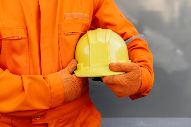 Vorderansicht des Arbeiters in der Uniform, die Schutzhelm hält