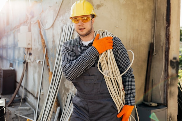 Kostenloses Foto vorderansicht des arbeiters mit tragendem schutzhelmseil