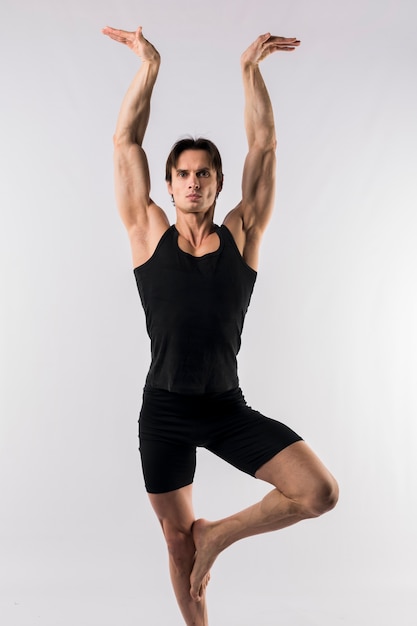 Vorderansicht des athletischen Mannes im Bodysuit, der eine Yogahaltung tut