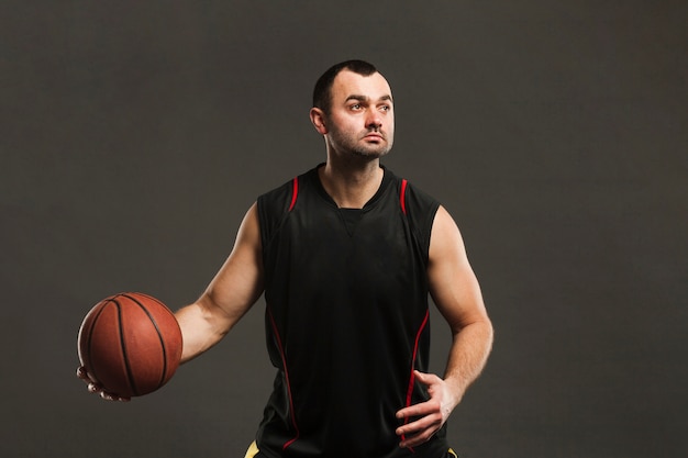 Kostenloses Foto vorderansicht des basketballspielers aufwerfend und mit ball spielend