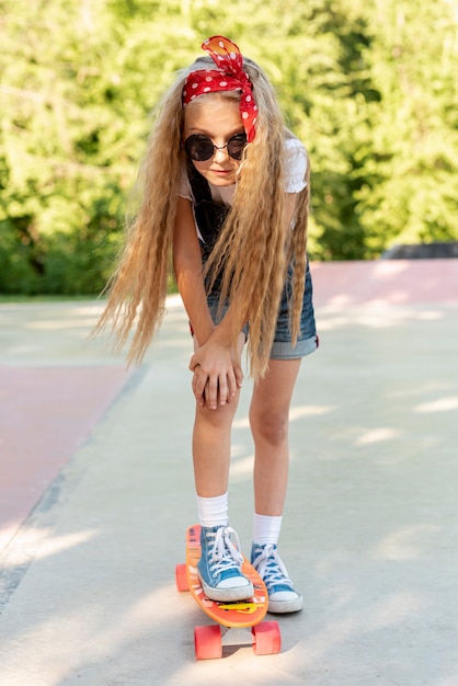 Vorderansicht des blonden Mädchens auf Skateboard