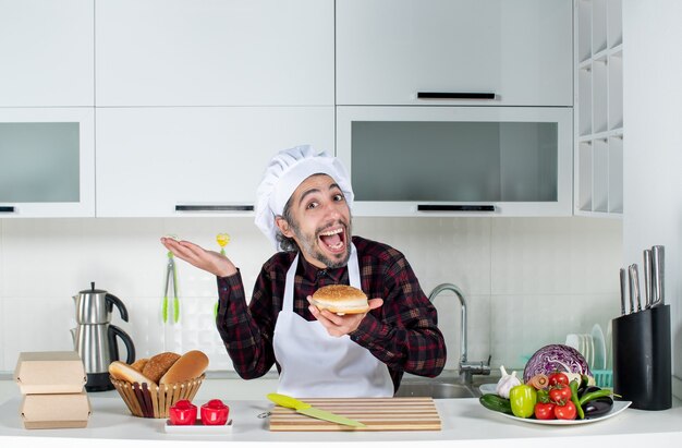 Vorderansicht des erfreuten männlichen Kochs, der Brot hält