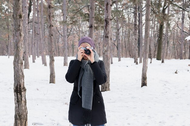 Vorderansicht des Frauenphotographen mit Kamera im Winter