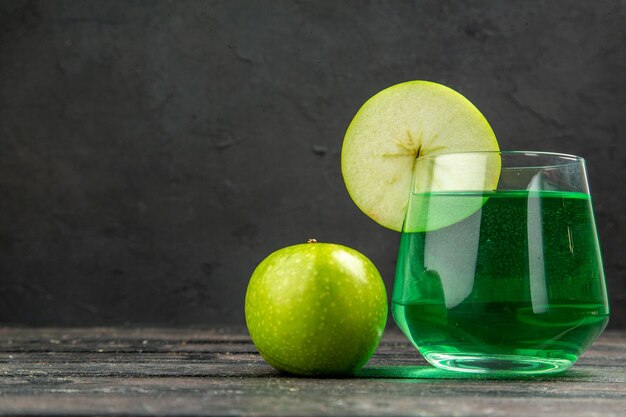 Vorderansicht des frischen natürlichen köstlichen Saftes in einem Glas und grünen Äpfeln auf schwarzem Hintergrund