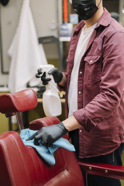 Vorderansicht des Friseurs, der den Stuhl reinigt