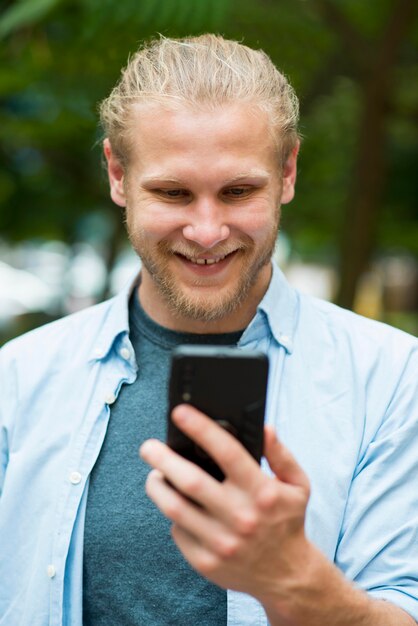 Vorderansicht des fröhlichen Mannes, der Telefon betrachtet