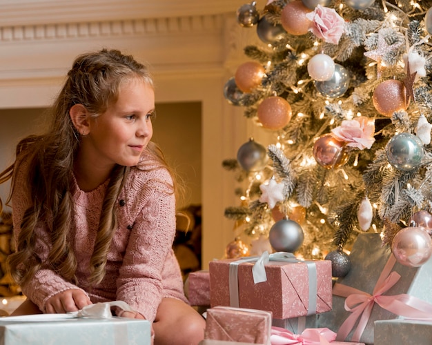 Vorderansicht des glücklichen Mädchens mit Geschenken und Weihnachtsbaum