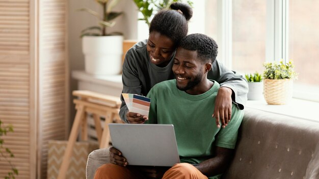 Vorderansicht des glücklichen Paares auf dem Sofa, das Pläne macht, Haus neu zu dekorieren