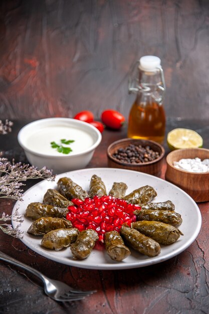 Vorderansicht des grünen Blattdolmas mit Granatäpfeln auf dunkler Oberfläche