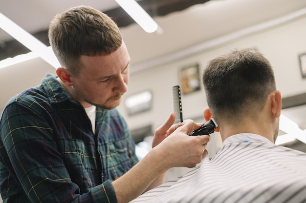 Kostenloses Foto vorderansicht des haarstilyst, der einen haarschnitt gibt