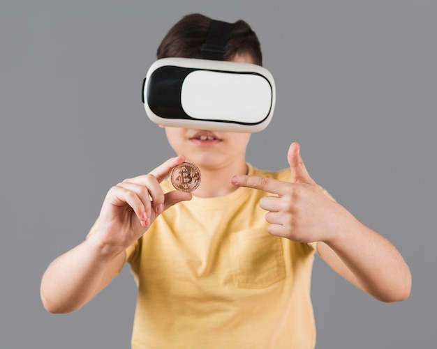 Kostenloses Foto vorderansicht des jungen, der bitcoin hält, während das virtual-reality-headset trägt