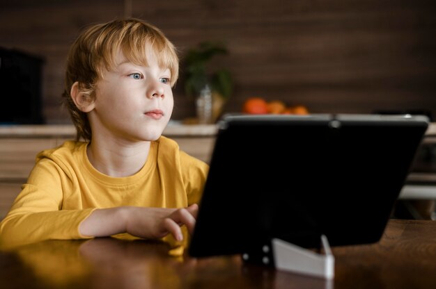 Vorderansicht des Jungen, der Tablette zu Hause verwendet