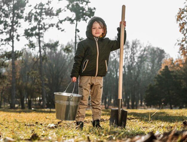 Vorderansicht des Jungen im Freien, der Eimer und Schaufel hält