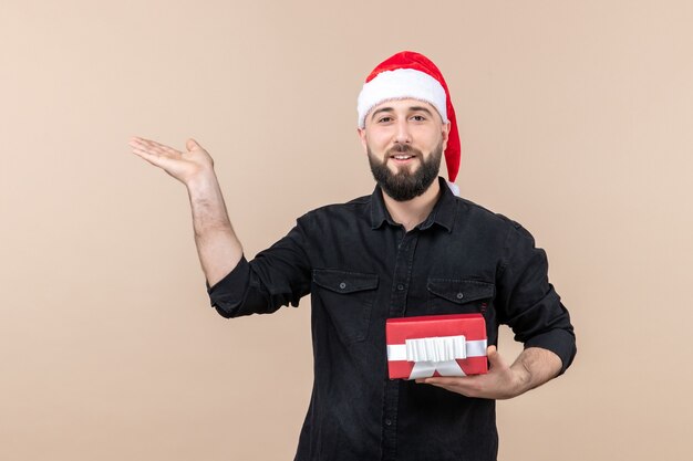 Vorderansicht des jungen Mannes, der Geschenk an der rosa Wand hält