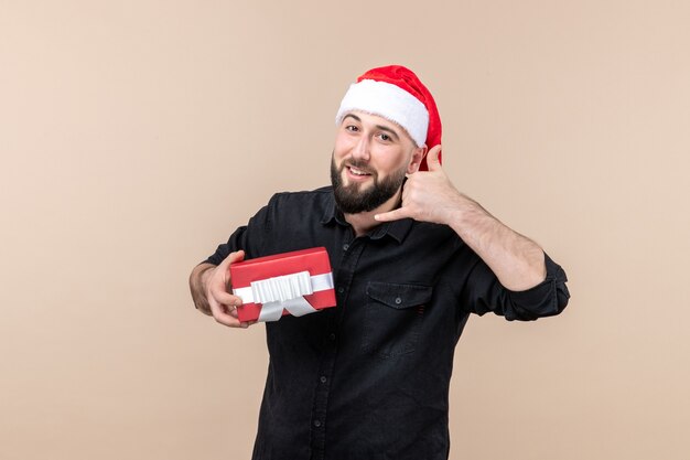 Vorderansicht des jungen Mannes, der Geschenk an der rosa Wand hält