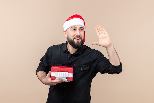 Vorderansicht des jungen Mannes, der Geschenk an der rosa Wand hält