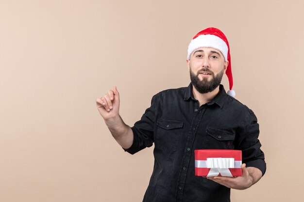 Vorderansicht des jungen Mannes, der Geschenk an der rosa Wand hält