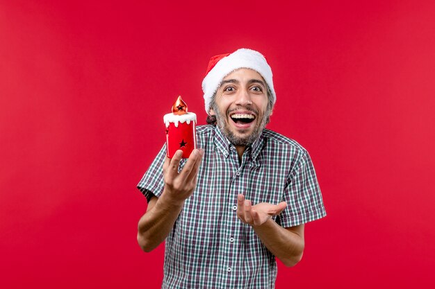 Vorderansicht des jungen Mannes, der kleines Ferienspielzeug auf Rot hält