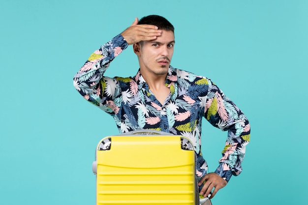Kostenloses Foto vorderansicht des jungen mannes, der reise mit seiner gelben tasche an der blauen wand vorbereitet