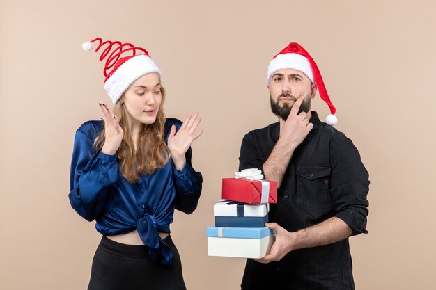 Vorderansicht des jungen Mannes, der Weihnachtsgeschenke mit Frau an der rosa Wand hält
