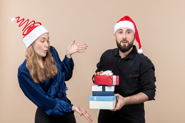 Vorderansicht des jungen Mannes, der Weihnachtsgeschenke mit Frau an der rosa Wand hält