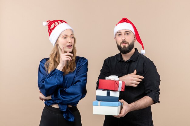 Vorderansicht des jungen Mannes, der Weihnachtsgeschenke mit Frau an der rosa Wand hält