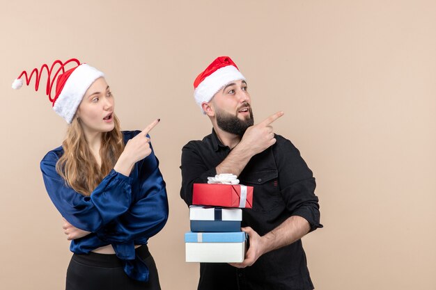 Vorderansicht des jungen Mannes, der Weihnachtsgeschenke mit Frau an der rosa Wand hält