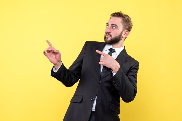 Vorderansicht des jungen Mannes erstaunlicher Geschäftsmann, der Finger beiseite auf Gelb zeigt