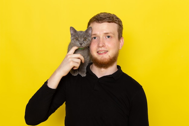 Kostenloses Foto vorderansicht des jungen mannes im schwarzen hemd, das niedliche graue katze hält