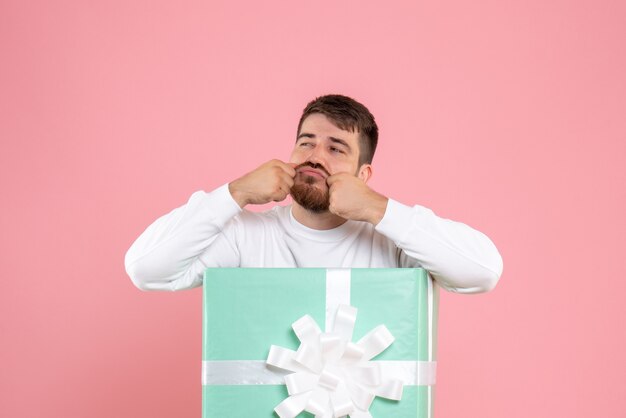 Vorderansicht des jungen Mannes innerhalb der gegenwärtigen Box an der rosa Wand