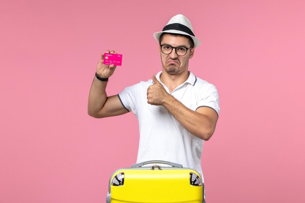 Vorderansicht des jungen Mannes mit Bankkarte an der rosa Wand pink