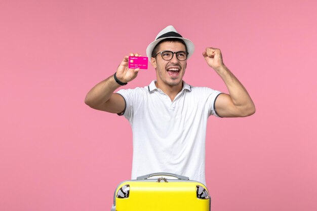 Vorderansicht des jungen Mannes mit Bankkarte an der rosa Wand pink