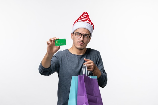 Vorderansicht des jungen Mannes mit Geschenken und Bankkarte auf weißer Wand