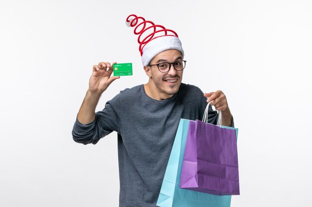 Vorderansicht des jungen Mannes mit Geschenken und Bankkarte auf weißer Wand