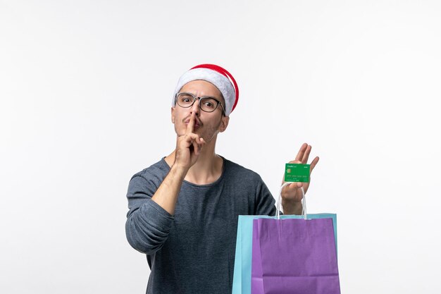 Vorderansicht des jungen Mannes mit Geschenken und Bankkarte auf weißer Wand