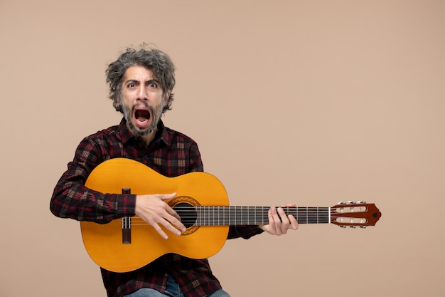 Vorderansicht des jungen Mannes mit Gitarre an der rosa Wand