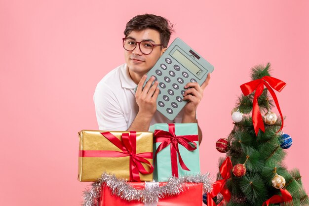 Vorderansicht des jungen Mannes um Weihnachten präsentiert das Halten des Rechners an der rosa Wand