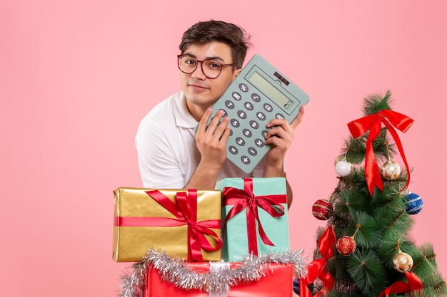 Vorderansicht des jungen Mannes um Weihnachten präsentiert das Halten des Rechners an der rosa Wand