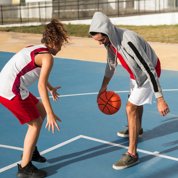 Vorderansicht des Jungen und des Mädchens, die Basketball spielen