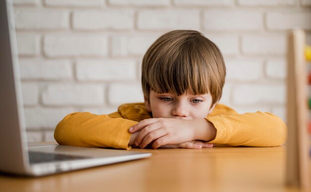 Vorderansicht des Kindes am Schreibtisch, das mit Laptop studiert