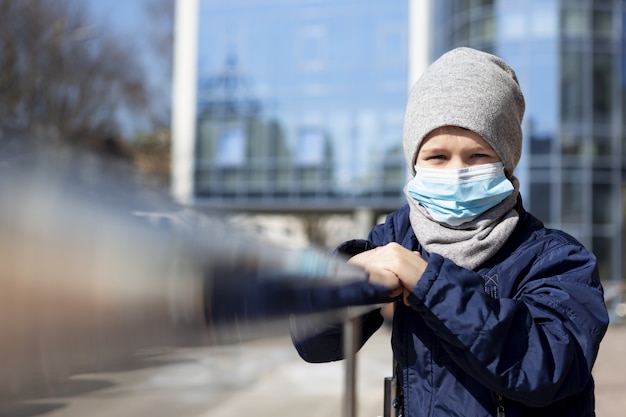 Vorderansicht des Kindes, das außerhalb mit medizinischer Maske aufwirft